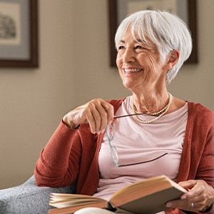 Senior woman smiling while reading at home