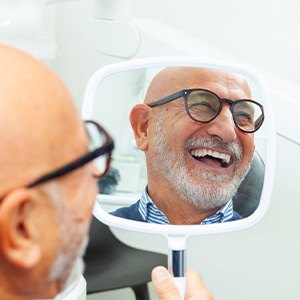 Man with black glasses smiling in reflection in mirror