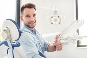 Man at the dentist smiling and holding a thumbs up